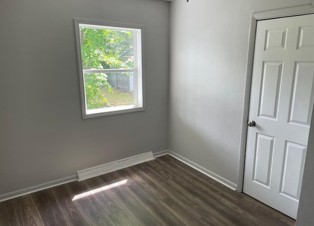 spare room with dark hardwood / wood-style flooring and a baseboard radiator