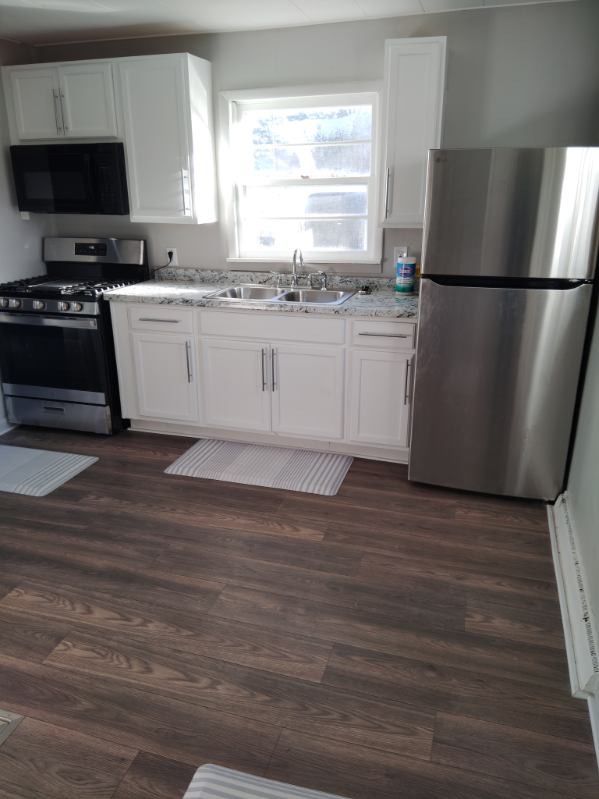 kitchen with white cabinets, sink, light stone countertops, appliances with stainless steel finishes, and dark hardwood / wood-style flooring