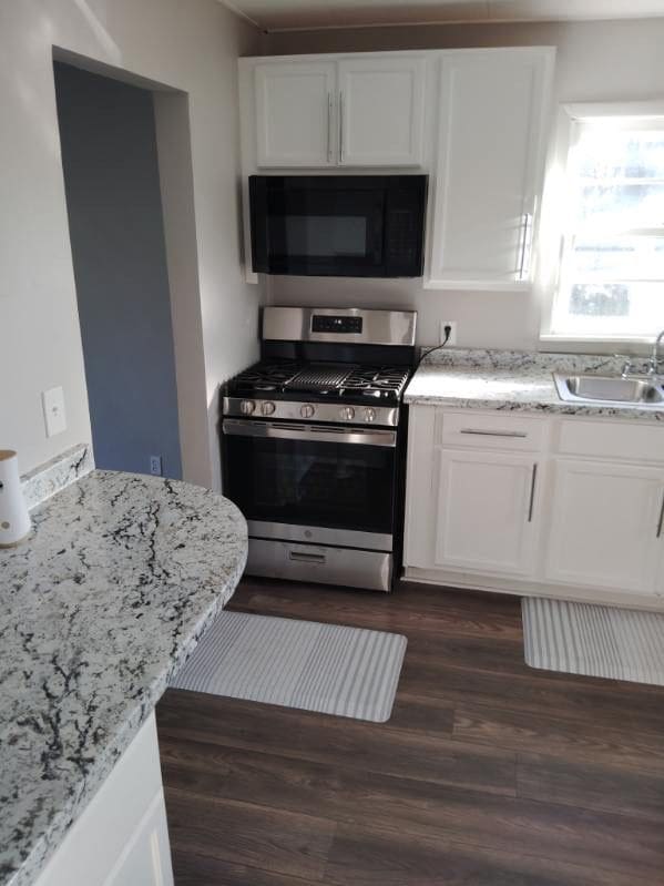 kitchen featuring light stone countertops, sink, white cabinets, dark hardwood / wood-style floors, and stainless steel range with gas cooktop