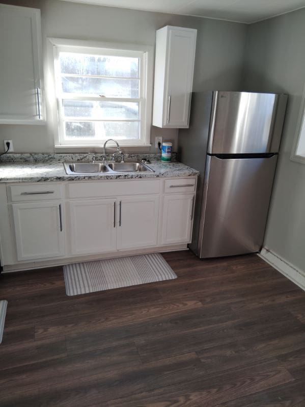 kitchen with white cabinets, stainless steel fridge, dark wood-type flooring, and sink