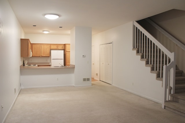 unfurnished living room with light carpet and sink