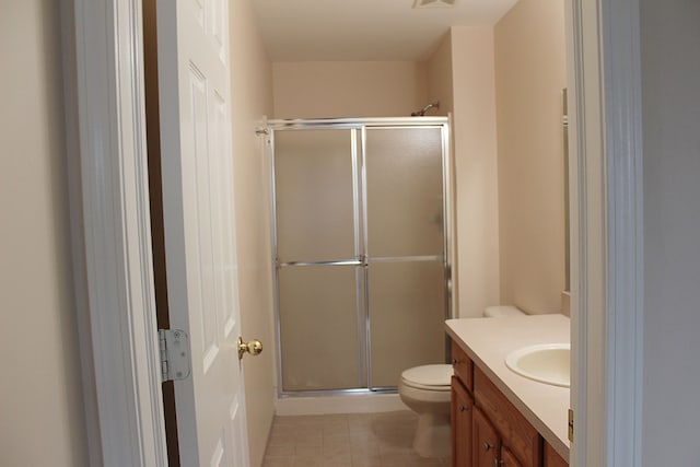 bathroom with tile patterned floors, vanity, toilet, and an enclosed shower