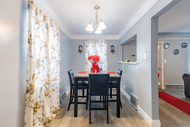 dining room with light wood-type flooring and a notable chandelier