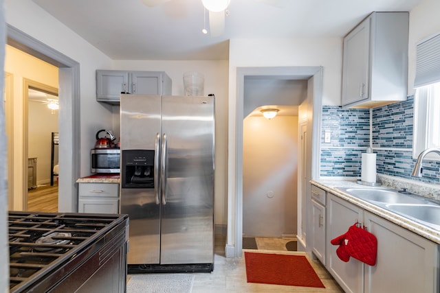 kitchen featuring gray cabinetry, decorative backsplash, sink, and stainless steel appliances