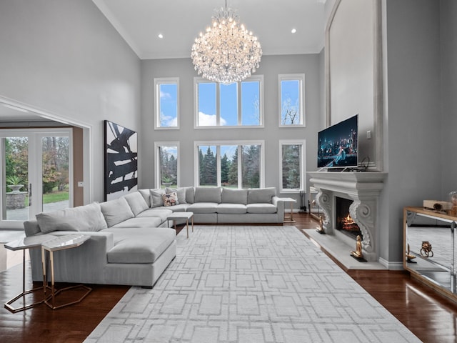 living room featuring hardwood / wood-style floors, a notable chandelier, a large fireplace, and a high ceiling