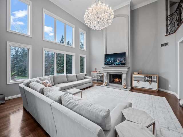 living room featuring dark hardwood / wood-style floors, a towering ceiling, ornamental molding, and a chandelier