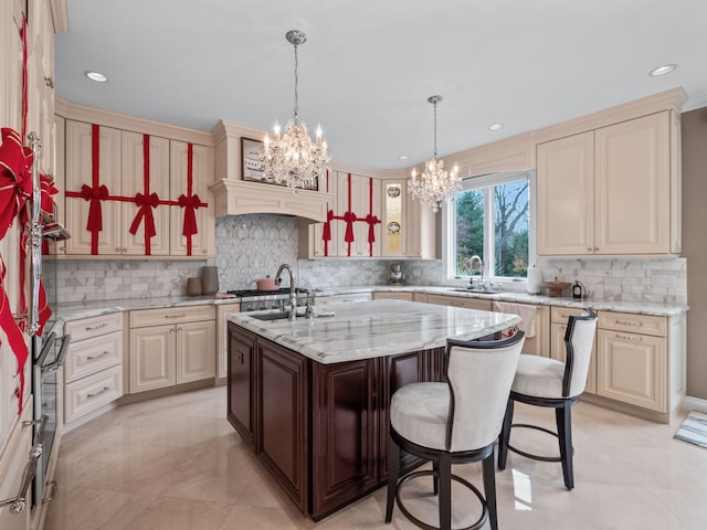 kitchen featuring a kitchen breakfast bar, sink, a kitchen island with sink, and an inviting chandelier