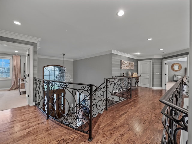 corridor featuring crown molding, plenty of natural light, a notable chandelier, and hardwood / wood-style flooring