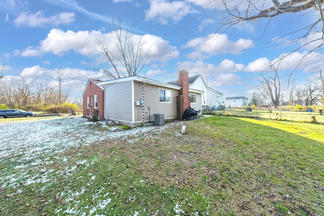 view of property exterior with central AC and a lawn