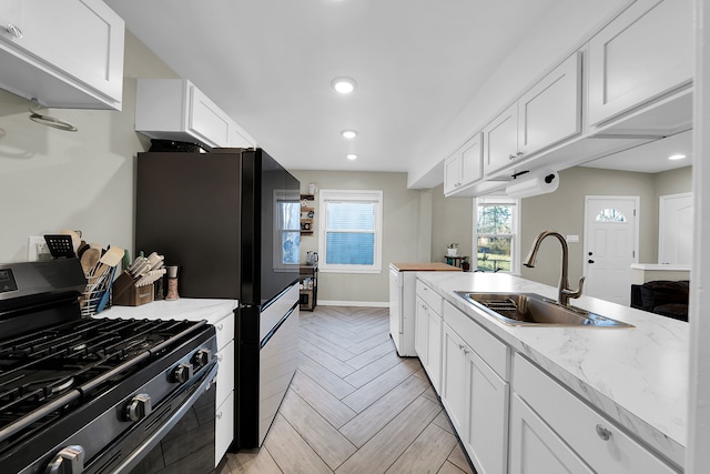 kitchen featuring white cabinetry, sink, black appliances, and light stone counters