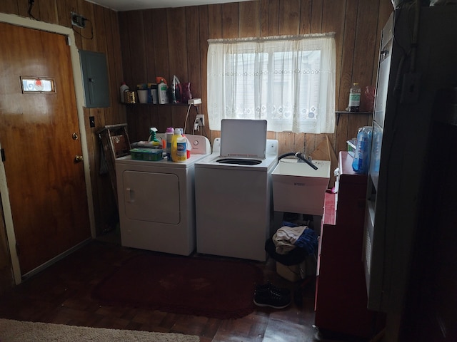 washroom featuring dark wood-type flooring, wooden walls, washer and dryer, sink, and electric panel