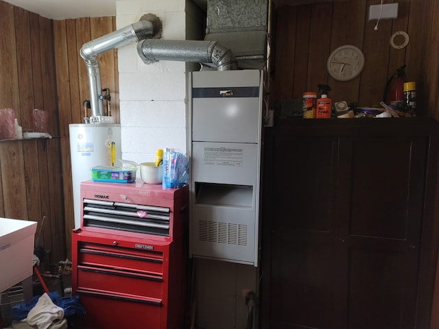 kitchen with gas water heater, sink, wooden walls, and heating unit