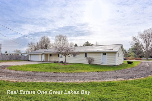 single story home featuring a front lawn, central air condition unit, and a garage