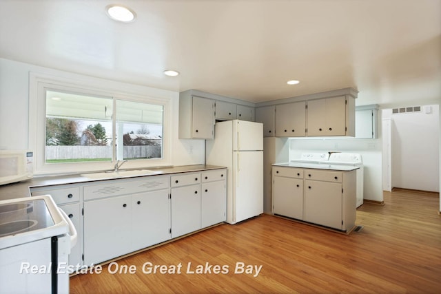 kitchen with gray cabinets, sink, white appliances, and light wood-type flooring