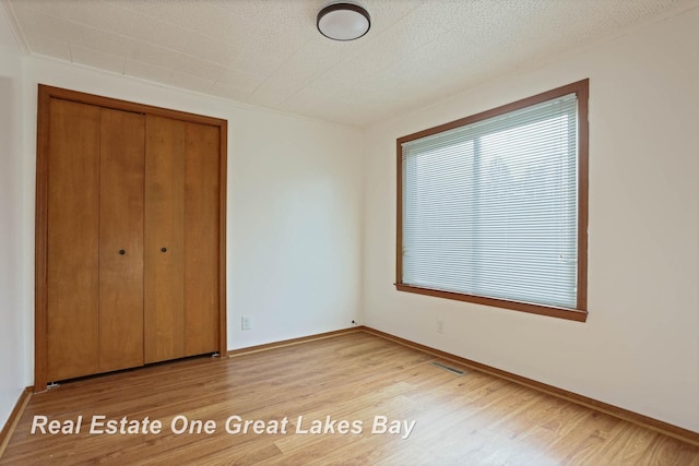 unfurnished bedroom featuring light wood-type flooring and a closet