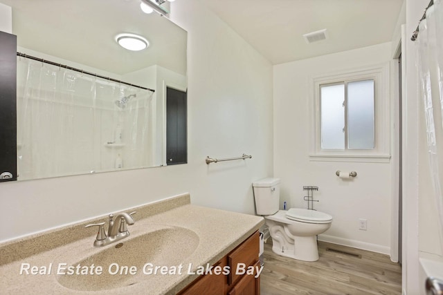 bathroom with hardwood / wood-style floors, toilet, vanity, and a shower with curtain