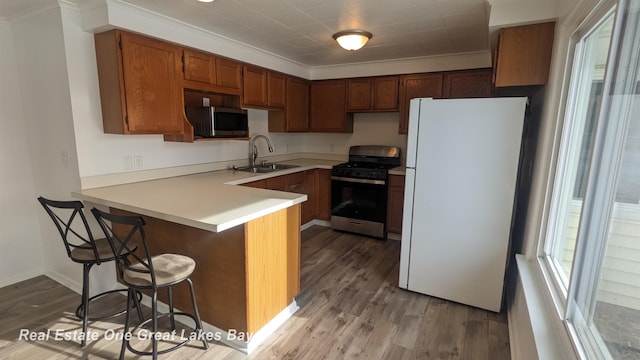 kitchen featuring sink, a breakfast bar, stainless steel appliances, kitchen peninsula, and light wood-type flooring