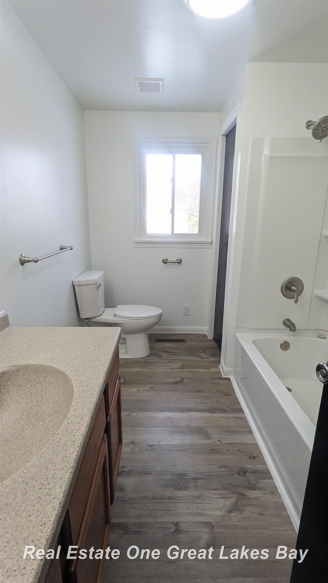 full bathroom featuring hardwood / wood-style flooring, vanity,  shower combination, and toilet