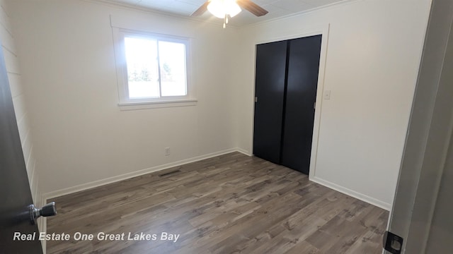 unfurnished bedroom with ceiling fan, wood-type flooring, a closet, and crown molding