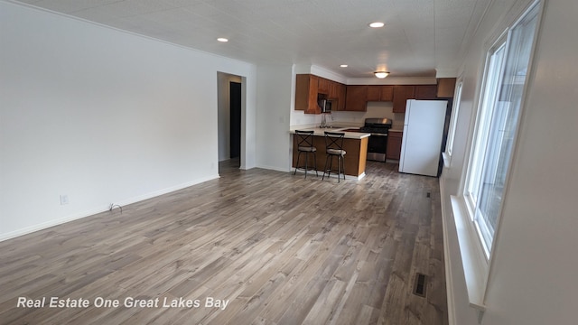 kitchen with a kitchen island, stainless steel appliances, light hardwood / wood-style floors, sink, and a breakfast bar area