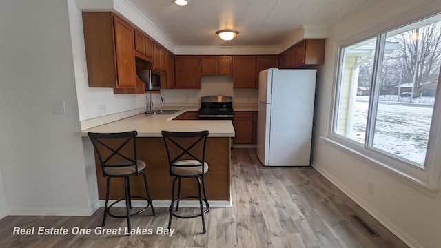 kitchen with stainless steel appliances, sink, light wood-type flooring, and kitchen peninsula