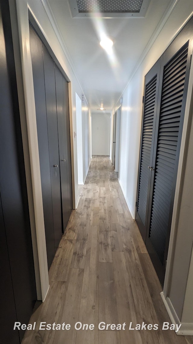 corridor with hardwood / wood-style flooring and ornamental molding