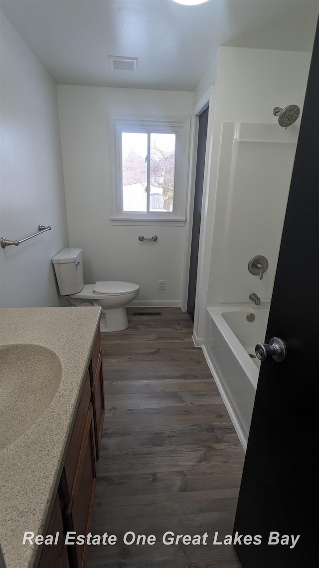 full bathroom with tub / shower combination, wood-type flooring, toilet, and vanity