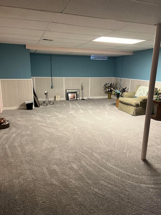 basement featuring a paneled ceiling and carpet floors