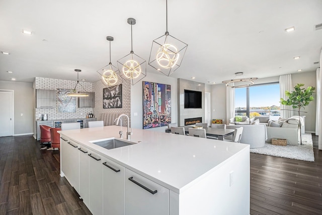 kitchen with pendant lighting, white cabinetry, a kitchen island with sink, and sink