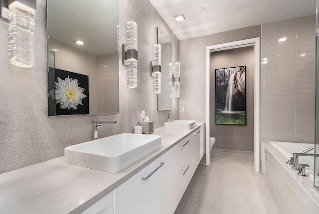 bathroom featuring tile patterned flooring, a relaxing tiled tub, toilet, and vanity