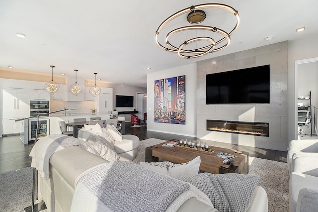 living room featuring a large fireplace, dark hardwood / wood-style flooring, and an inviting chandelier