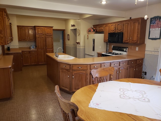 kitchen with range with gas cooktop, kitchen peninsula, sink, and white fridge