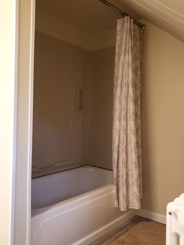 bathroom featuring vaulted ceiling, radiator, and shower / tub combo with curtain