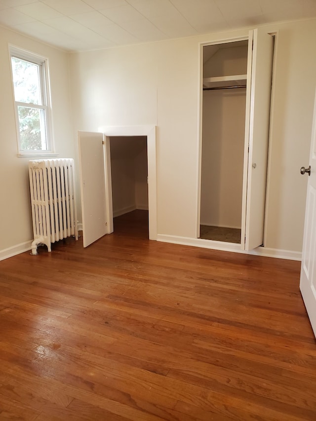 unfurnished bedroom with radiator and hardwood / wood-style floors