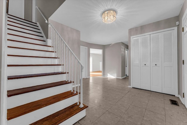 stairs with tile patterned flooring and an inviting chandelier