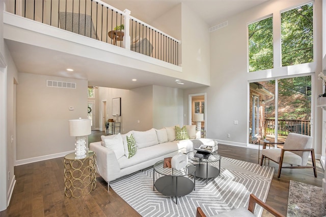 living room featuring a towering ceiling and dark wood-type flooring