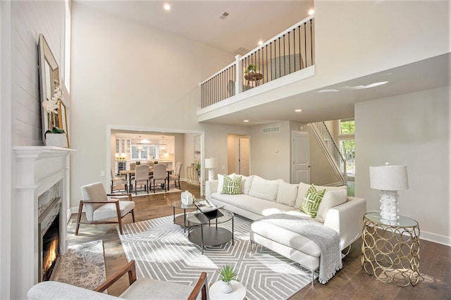 living room with a towering ceiling and dark wood-type flooring