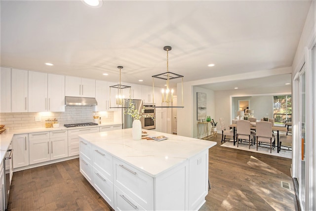 kitchen featuring dark hardwood / wood-style flooring, stainless steel appliances, white cabinets, a center island, and hanging light fixtures