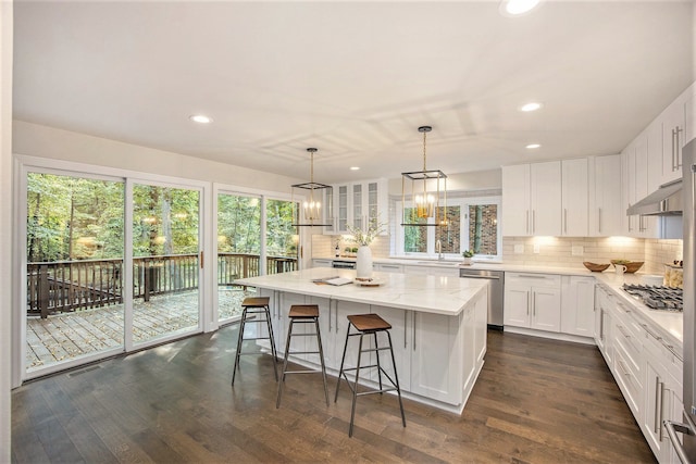 kitchen with white cabinets, stainless steel appliances, a kitchen island, and a healthy amount of sunlight