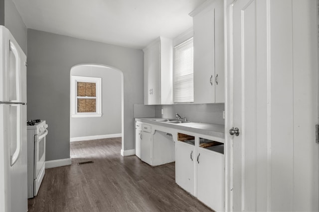 kitchen with white cabinets, sink, white appliances, and dark wood-type flooring