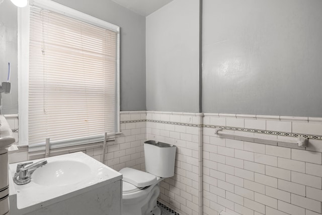 bathroom featuring vanity, toilet, and tile walls