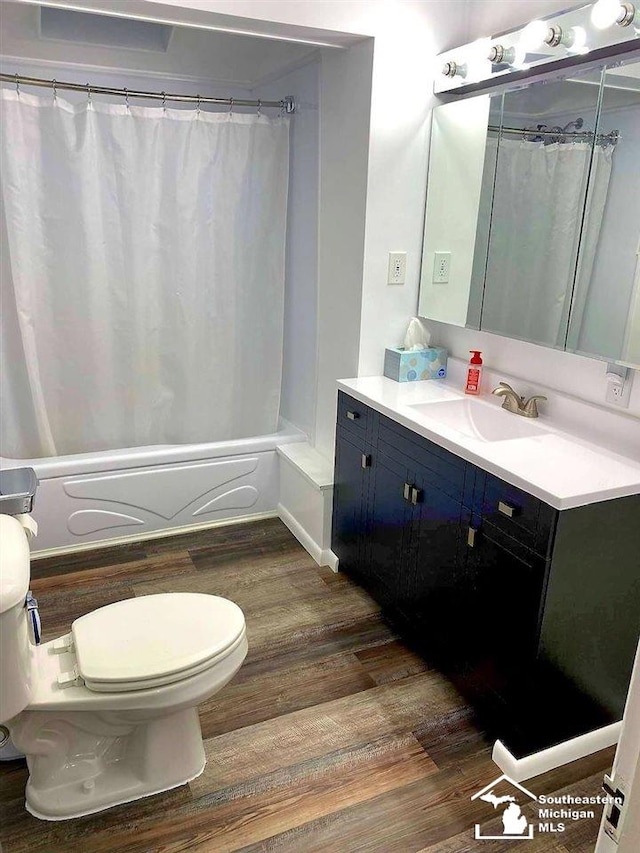 bathroom featuring toilet, vanity, shower / tub combo with curtain, and wood finished floors