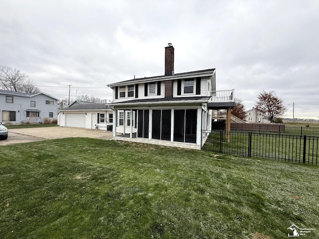 rear view of house featuring concrete driveway, a chimney, a lawn, fence, and a sunroom