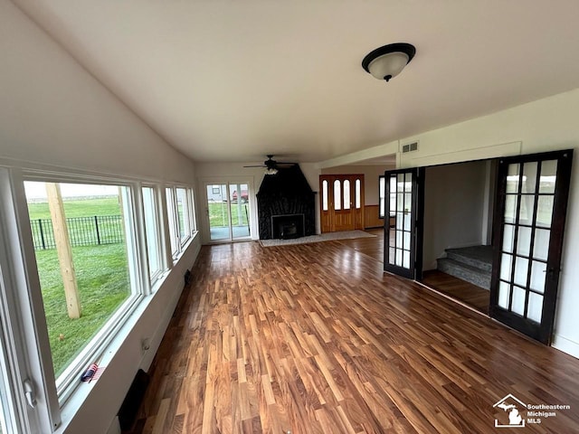 unfurnished living room with ceiling fan, lofted ceiling, and dark wood-type flooring