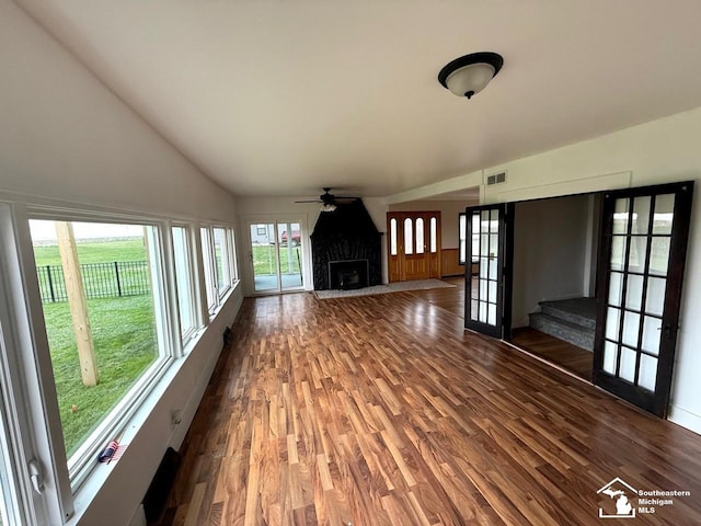 unfurnished living room with wood finished floors, a premium fireplace, visible vents, a ceiling fan, and high vaulted ceiling