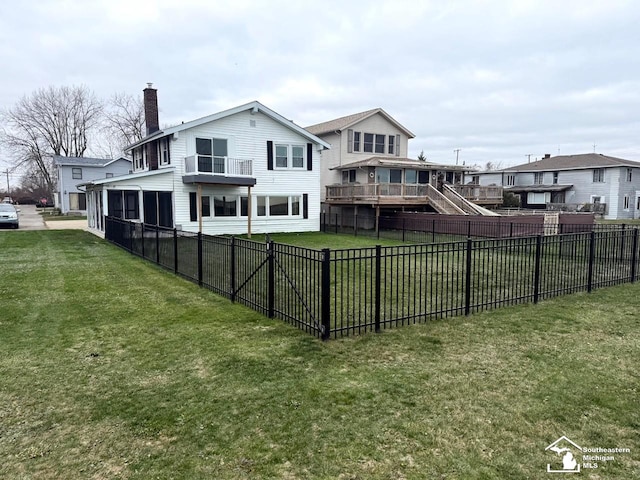 rear view of property featuring a lawn, a fenced backyard, and a chimney