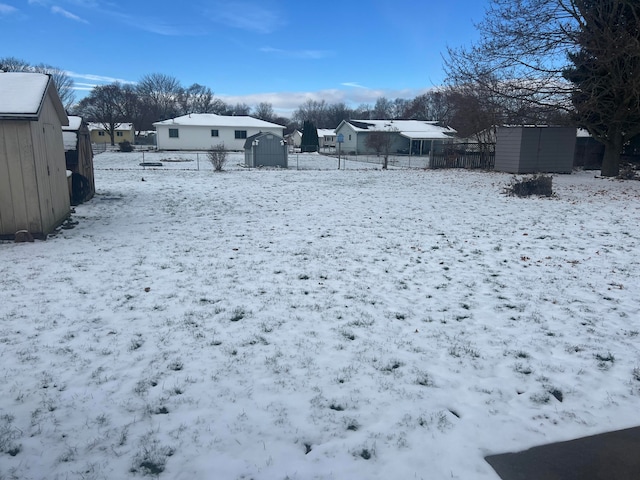 yard layered in snow featuring a storage unit