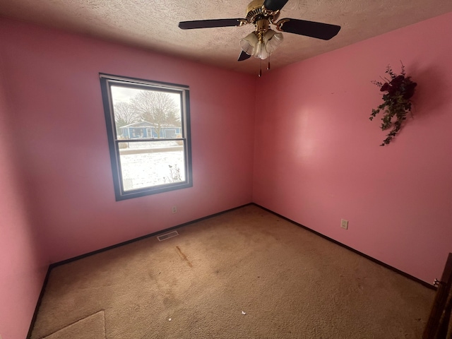 carpeted spare room with ceiling fan and a textured ceiling