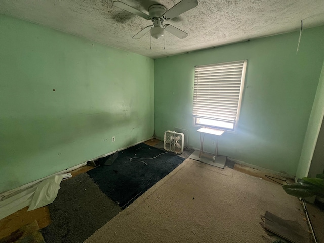 carpeted spare room featuring ceiling fan and a textured ceiling