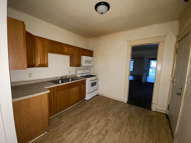 kitchen with sink, white appliances, and hardwood / wood-style floors